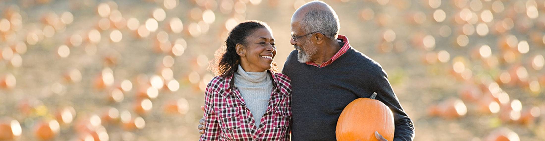 senior couple enjoy picking a pumpkin at a pumpkin patch