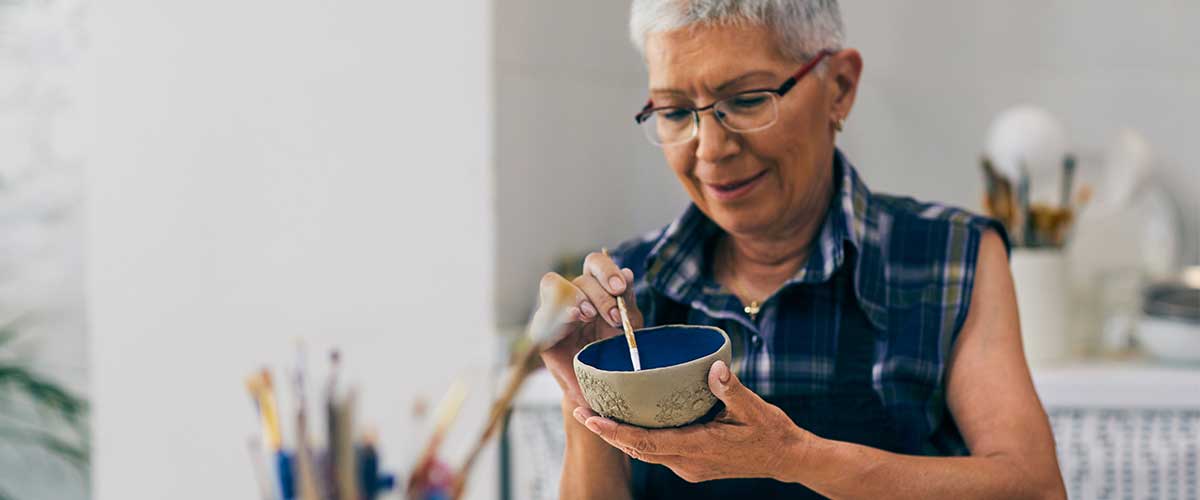 a senior woman making a clay bowl