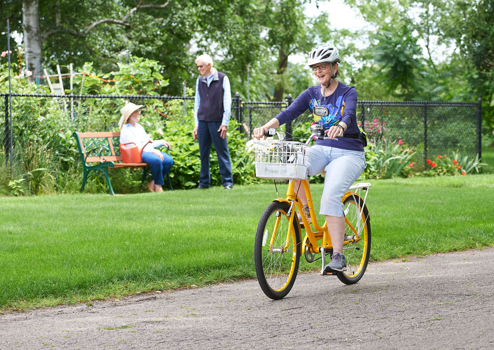resident riding a bicycle on a trail near the facility