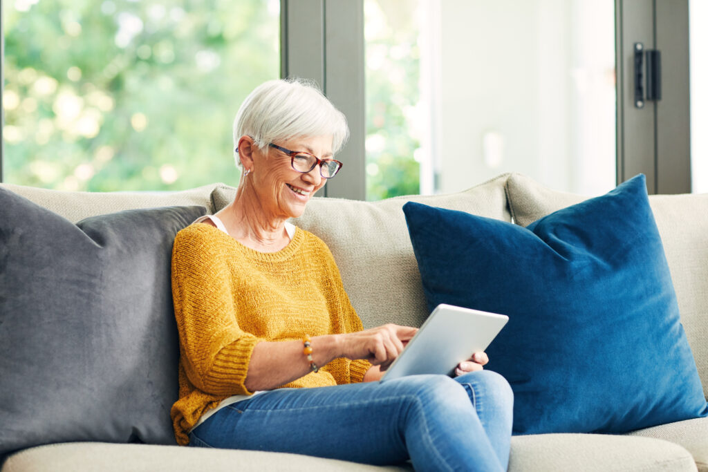 senior looking at an ipad seated on the couch
