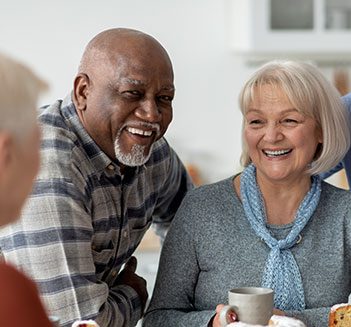 A group of seniors smile and chat over coffee.