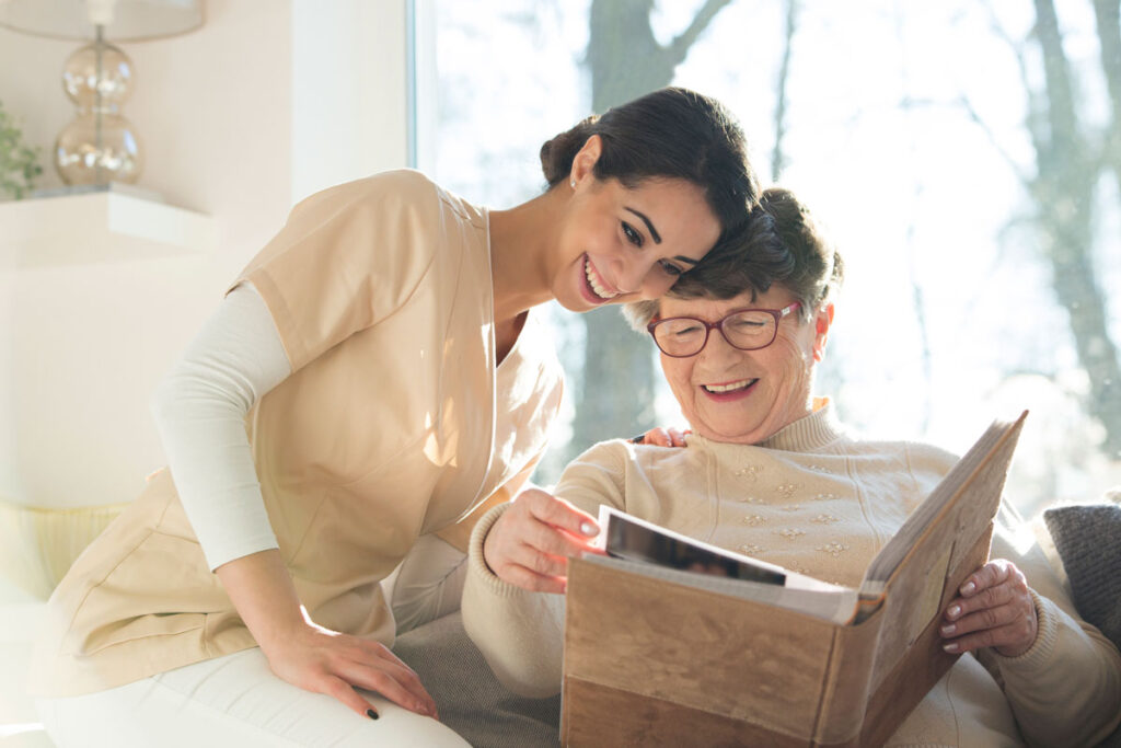 A senior woman looking at a photo album with a skilled nurse.