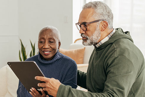 A senior couple look at a tablet together.