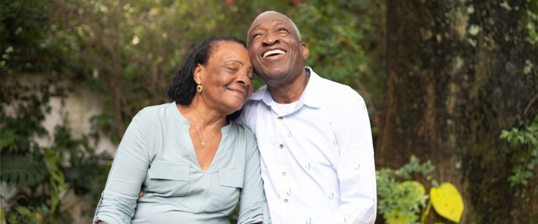 A woman leans into her husband as they pose outside for a photo