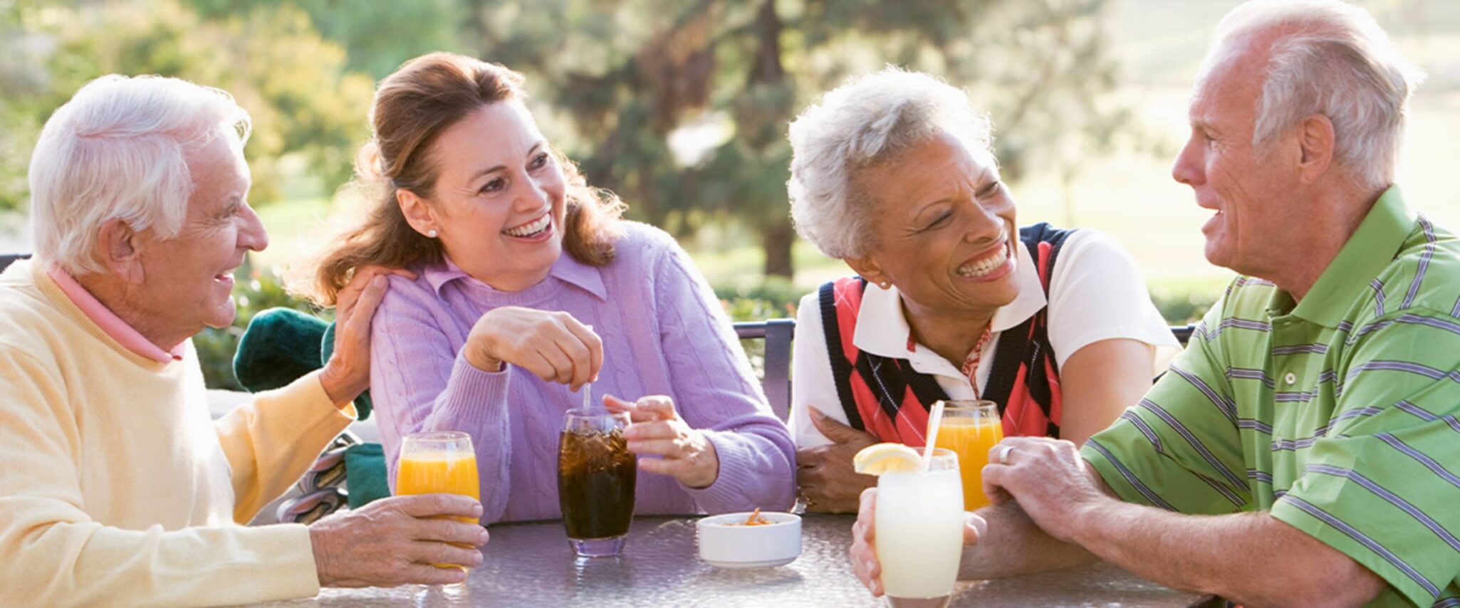 Group of seniors sitting outside having drinks in their senior living community