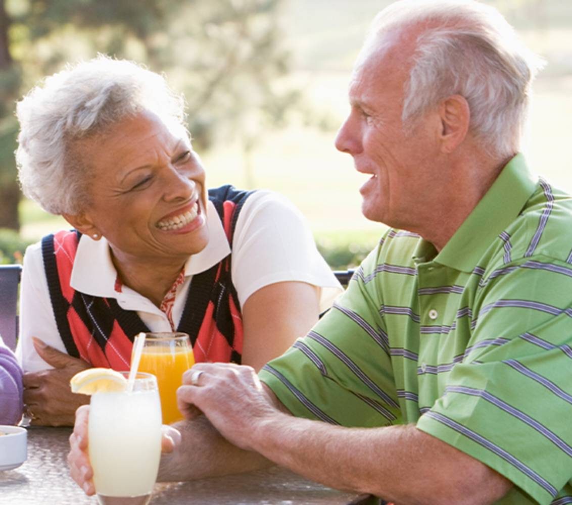 Group of seniors sitting outside having drinks in their senior living community