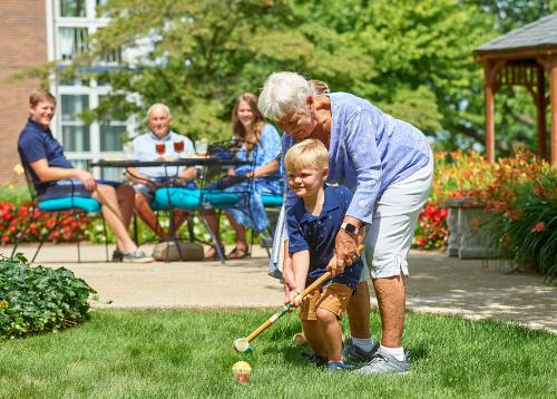 senior helping kid play croquet