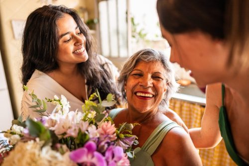 Young sisters giving flowers to mother at home